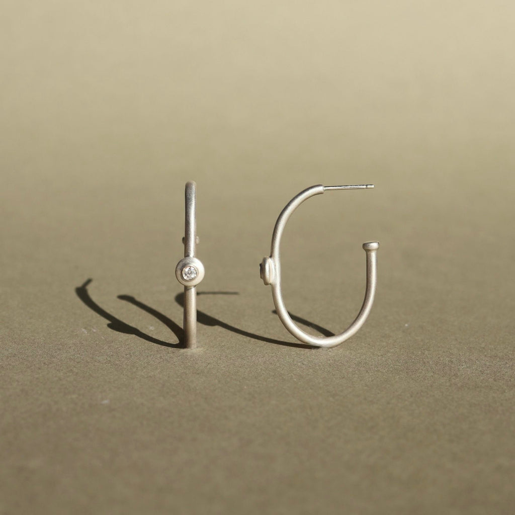 Sterling silver hoop earrings with natural diamond accents and a minimalist design.