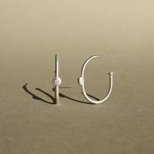 Sterling silver hoop earrings with natural diamond accents and a minimalist design.